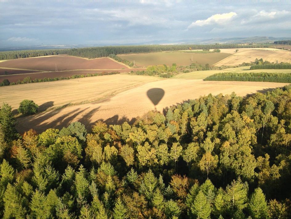 A beautiful shadow of the hot air balloon over the fields in the distance.
